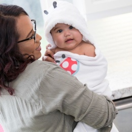 Mama trzymająca dziecko w okryciu kąpielowym z kapturem na głowie